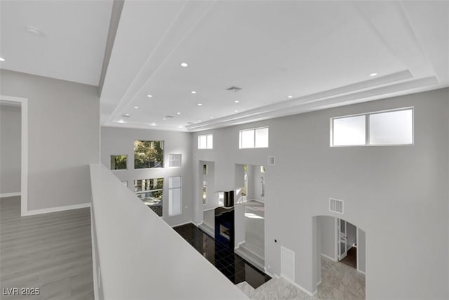 corridor featuring arched walkways, an upstairs landing, recessed lighting, and baseboards