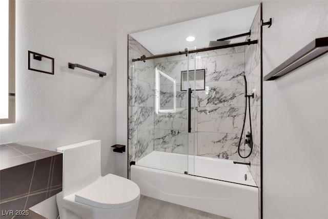 bathroom featuring toilet and bath / shower combo with glass door