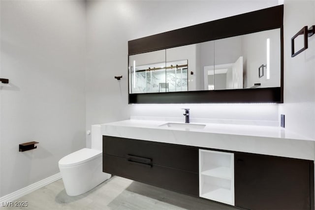 bathroom featuring baseboards, toilet, and vanity