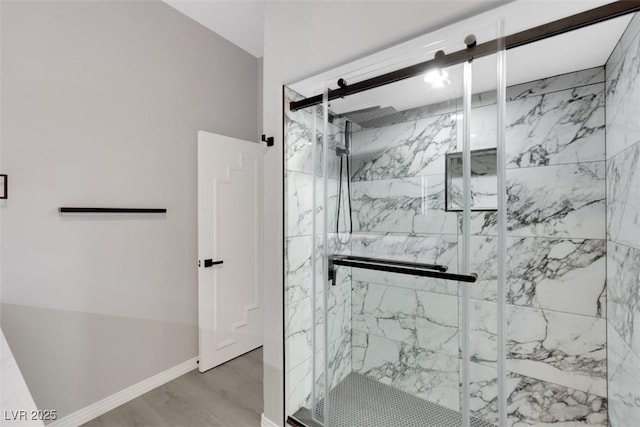 bathroom featuring a marble finish shower, baseboards, and wood finished floors