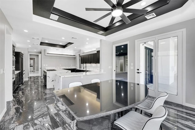 kitchen with visible vents, marble finish floor, a tray ceiling, dark cabinetry, and recessed lighting