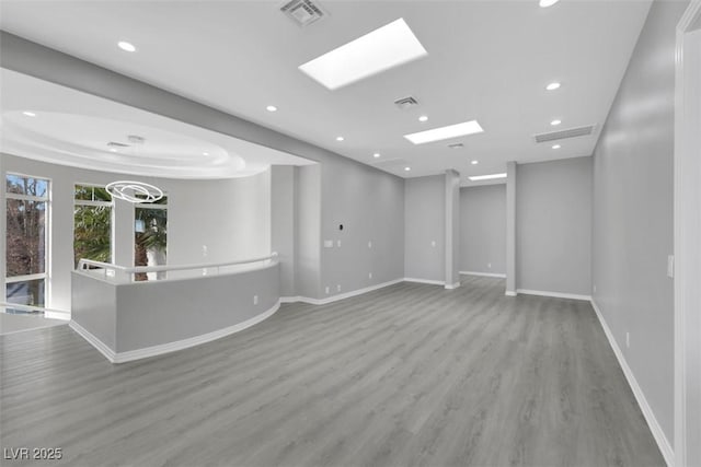 unfurnished room with visible vents, baseboards, recessed lighting, a skylight, and wood finished floors