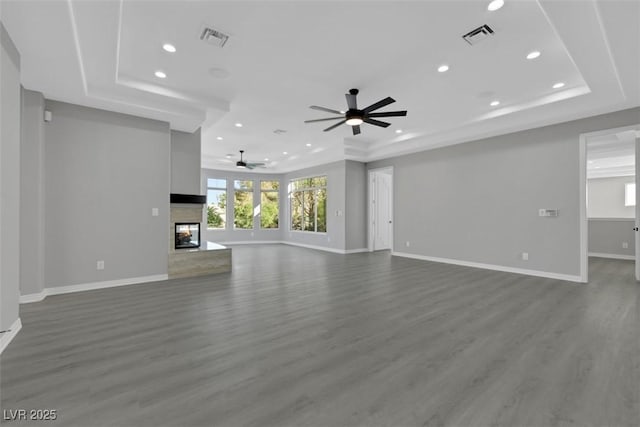 unfurnished living room featuring a tray ceiling, visible vents, and a multi sided fireplace