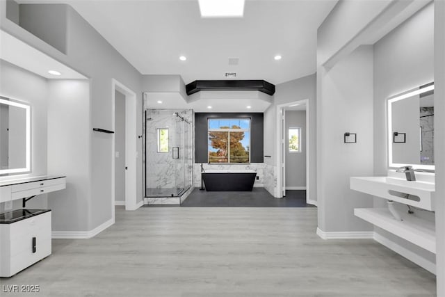 hallway featuring recessed lighting, baseboards, wood finished floors, and a sink