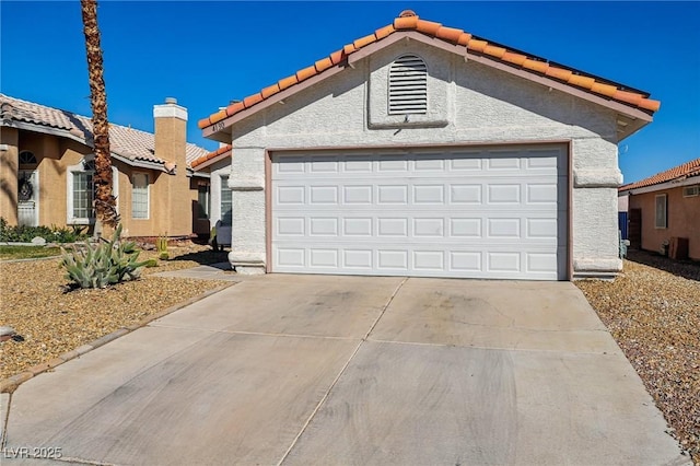 mediterranean / spanish home with stucco siding, a tile roof, an outdoor structure, concrete driveway, and a garage