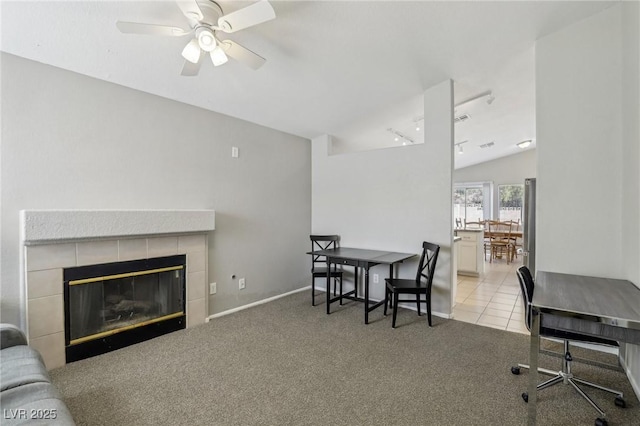 dining room with a tiled fireplace, light colored carpet, vaulted ceiling, light tile patterned floors, and rail lighting