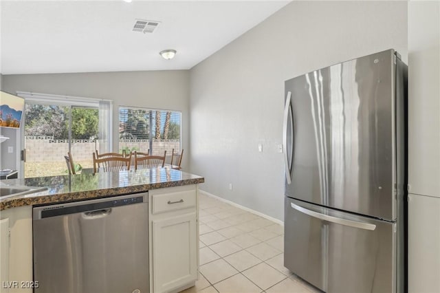 kitchen featuring visible vents, lofted ceiling, light tile patterned floors, white cabinets, and stainless steel appliances