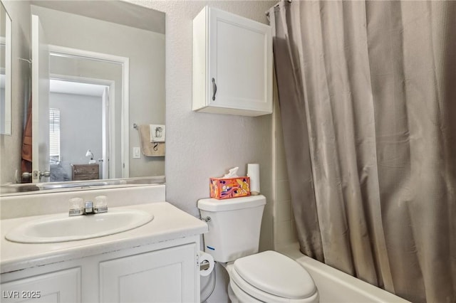 bathroom with toilet, vanity, shower / bath combo, and a textured wall