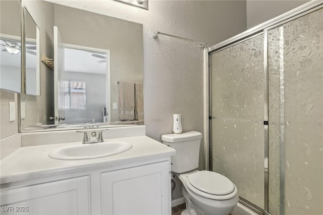 bathroom featuring a shower stall, toilet, vanity, and a textured wall