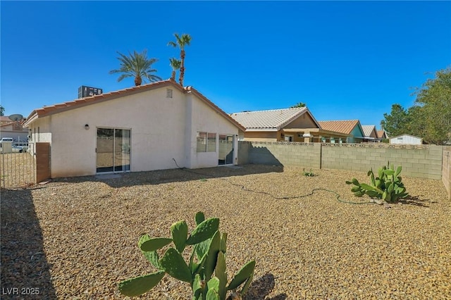 back of house with a fenced backyard, central AC, and stucco siding