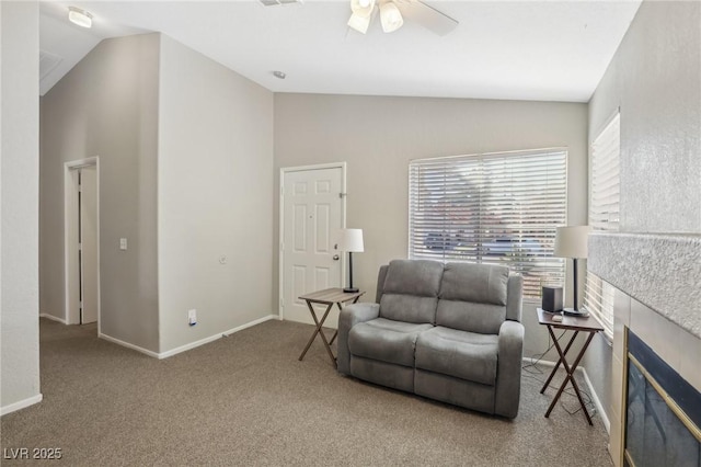 living area featuring a ceiling fan, carpet, baseboards, a fireplace, and vaulted ceiling