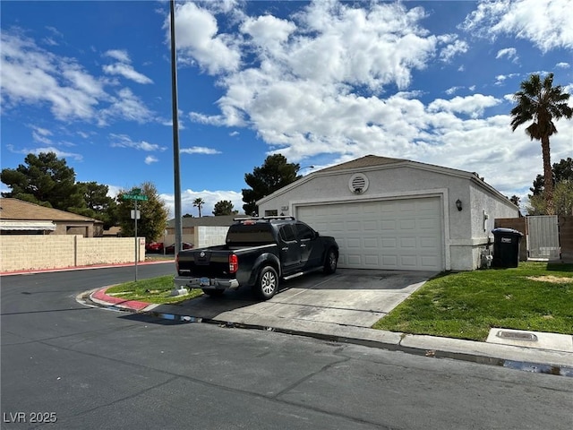 exterior space featuring stucco siding, an attached garage, driveway, and fence