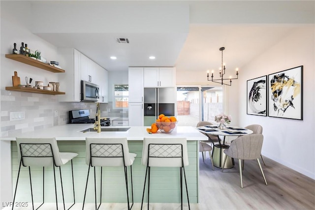 kitchen featuring tasteful backsplash, visible vents, light countertops, appliances with stainless steel finishes, and a peninsula