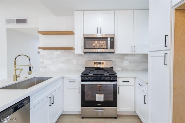 kitchen featuring visible vents, a sink, open shelves, white cabinetry, and appliances with stainless steel finishes