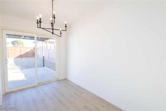 unfurnished dining area featuring a notable chandelier and wood finished floors