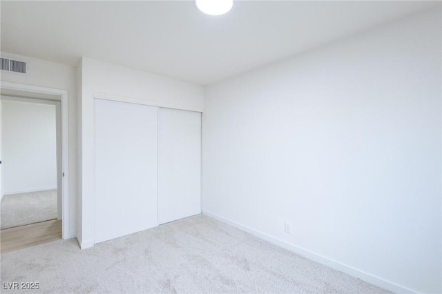 unfurnished bedroom with carpet flooring, baseboards, visible vents, and a closet