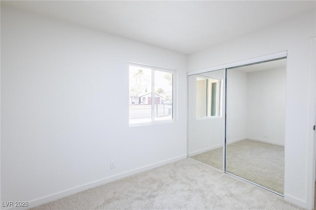 unfurnished bedroom featuring baseboards, carpet floors, and a closet