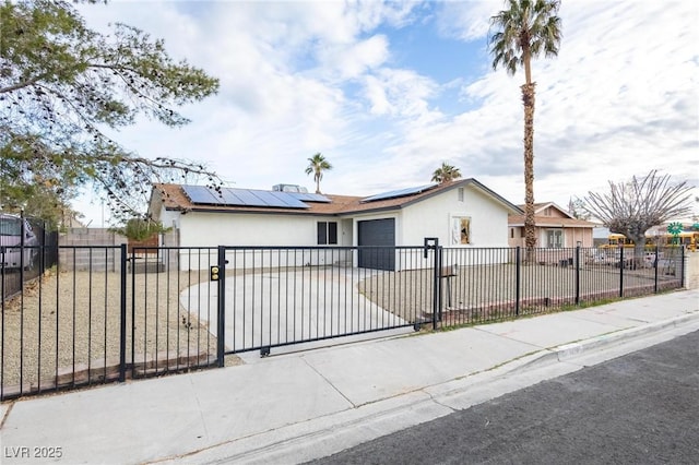 view of front of property featuring a fenced front yard, stucco siding, solar panels, and concrete driveway