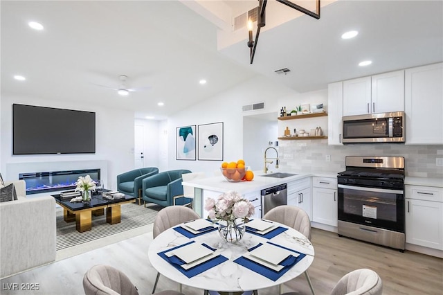 kitchen featuring visible vents, a sink, stainless steel appliances, white cabinets, and light wood-type flooring