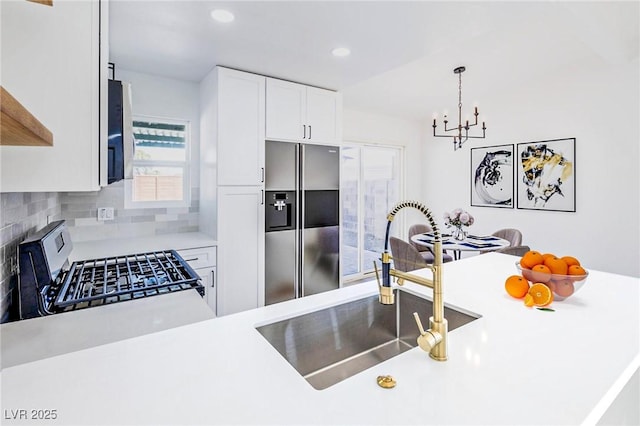 kitchen with tasteful backsplash, light countertops, stainless steel appliances, white cabinetry, and a sink