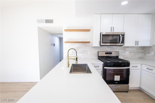 kitchen with visible vents, open shelves, a sink, stainless steel appliances, and white cabinetry