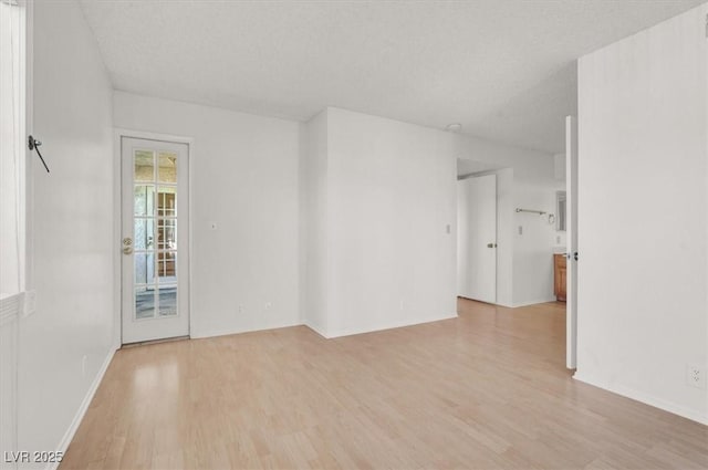 unfurnished room featuring light wood-style flooring and a textured ceiling