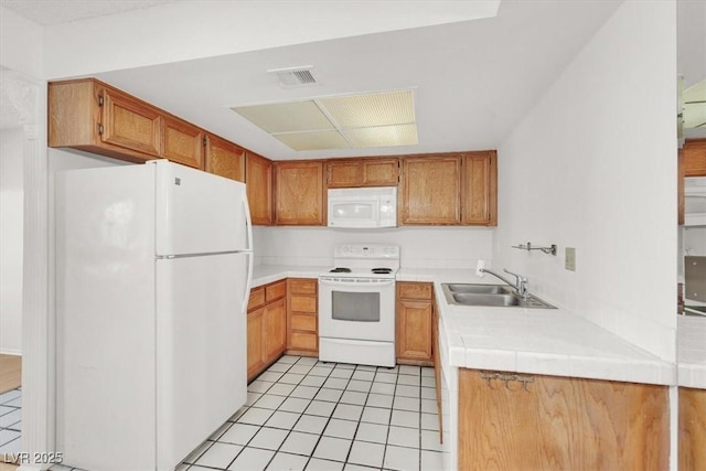 kitchen with visible vents, brown cabinets, a sink, white appliances, and light tile patterned flooring