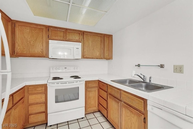 kitchen featuring tile countertops, light tile patterned floors, brown cabinetry, white appliances, and a sink