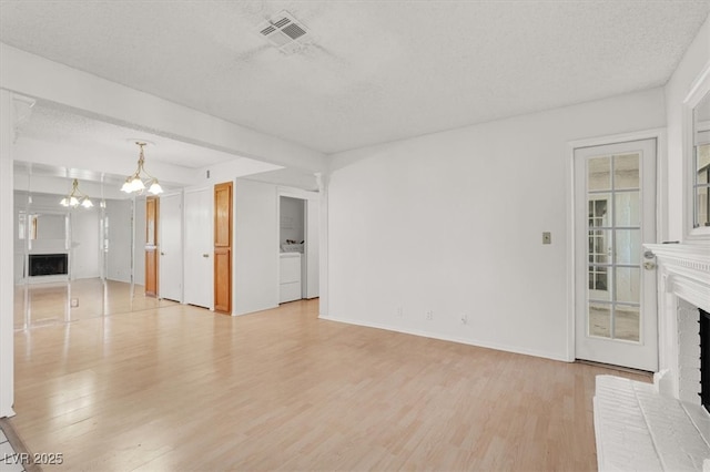 unfurnished living room featuring visible vents, light wood-style floors, and a fireplace