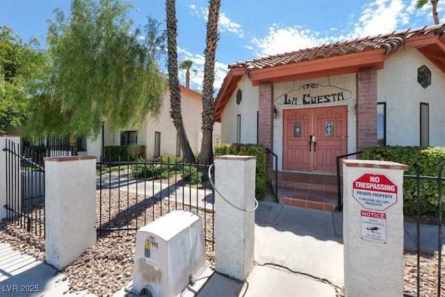 view of front of home featuring brick siding, stucco siding, a tile roof, and fence