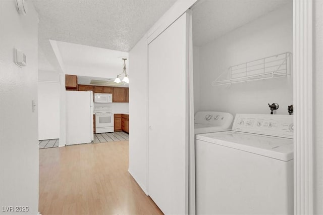 washroom featuring independent washer and dryer, laundry area, a textured ceiling, a notable chandelier, and light wood-type flooring