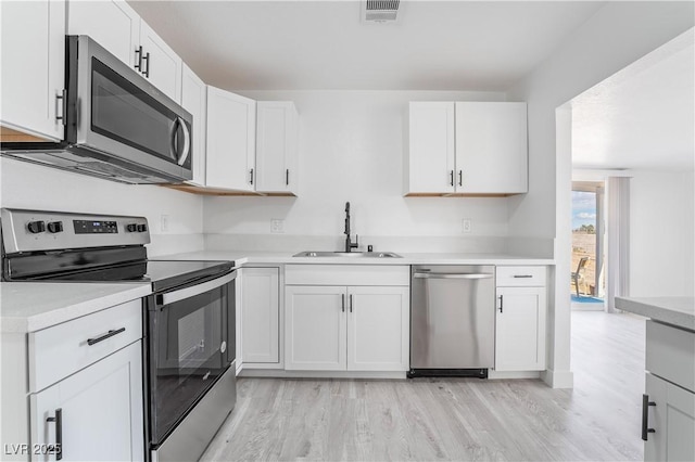 kitchen with visible vents, a sink, stainless steel appliances, light countertops, and white cabinetry