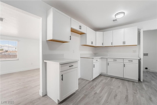 kitchen with visible vents, light wood-style flooring, light countertops, and baseboards