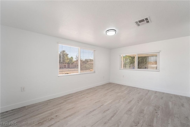 unfurnished room with visible vents, light wood-style floors, and baseboards