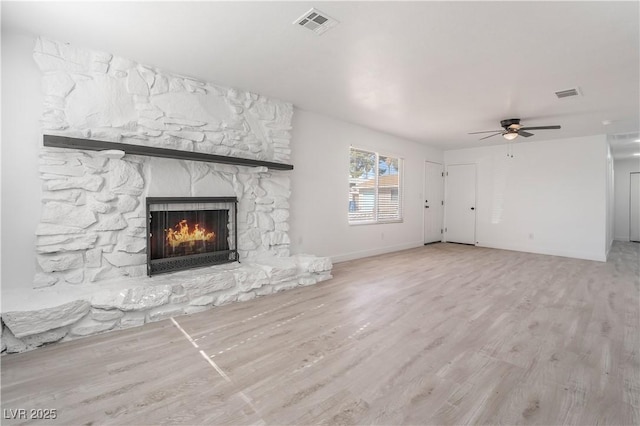 unfurnished living room featuring wood finished floors, a fireplace, visible vents, and ceiling fan