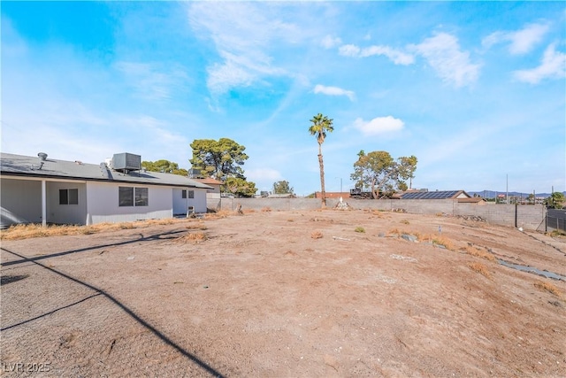 view of yard featuring fence and central AC