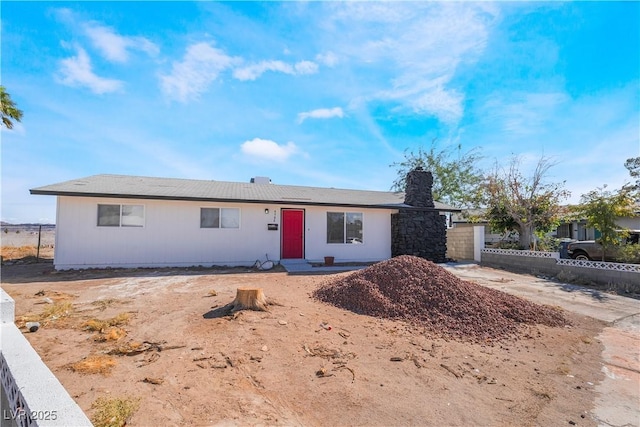 ranch-style home featuring a chimney and fence