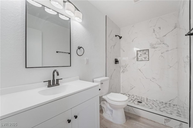 full bathroom with vanity, toilet, wood finished floors, and a marble finish shower