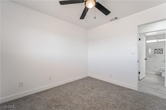 carpeted spare room featuring visible vents, a ceiling fan, and baseboards