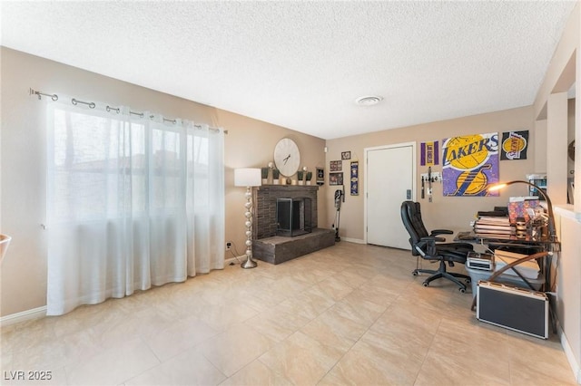 office area featuring a brick fireplace, a textured ceiling, and baseboards