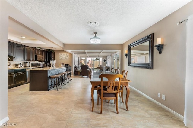 dining space featuring visible vents, a textured ceiling, and baseboards