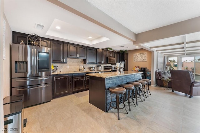 kitchen with visible vents, backsplash, dark brown cabinetry, a breakfast bar area, and stainless steel appliances