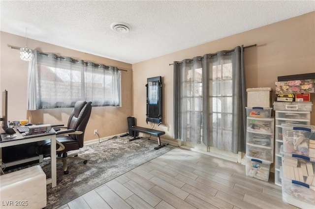 office area with baseboards, visible vents, a textured ceiling, and wood finish floors