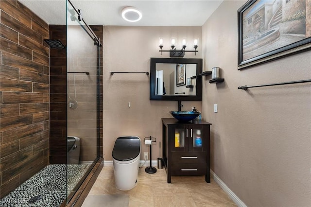 bathroom with a shower stall, toilet, baseboards, and a sink