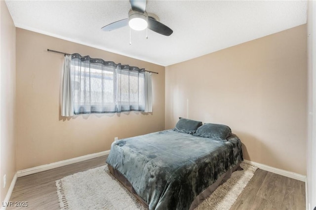 bedroom with baseboards, wood finished floors, and a ceiling fan