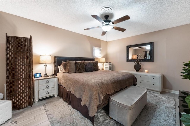 bedroom with a ceiling fan, light wood-style floors, and a textured ceiling