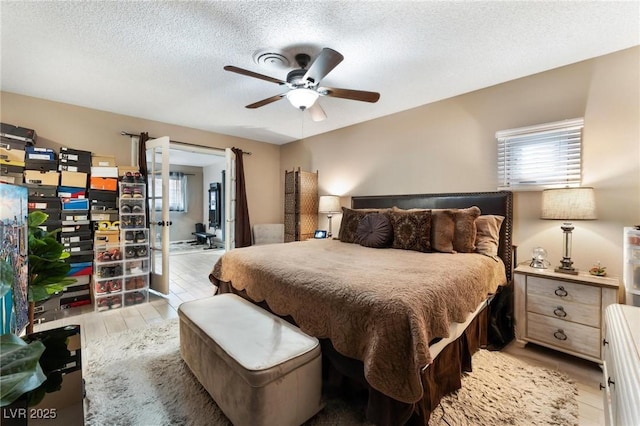 bedroom featuring a ceiling fan, light wood-type flooring, and a textured ceiling