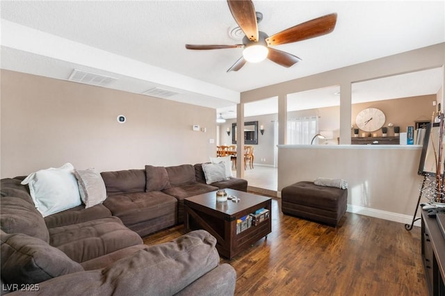 living area with visible vents, baseboards, wood finished floors, and a ceiling fan