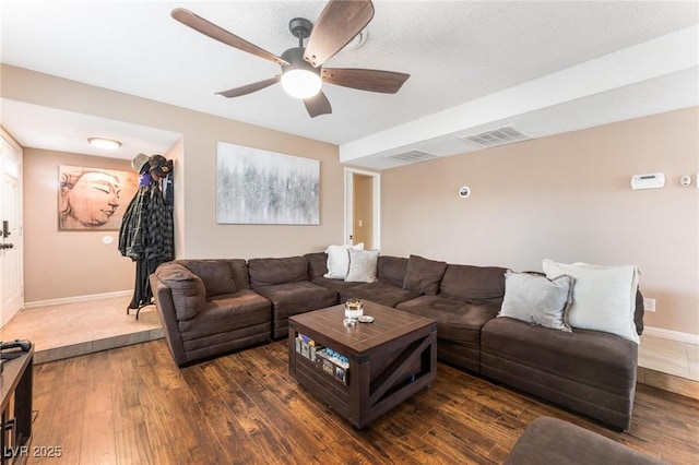 living area featuring visible vents, baseboards, dark wood finished floors, and a ceiling fan