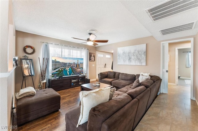 living room with baseboards, visible vents, a textured ceiling, and ceiling fan